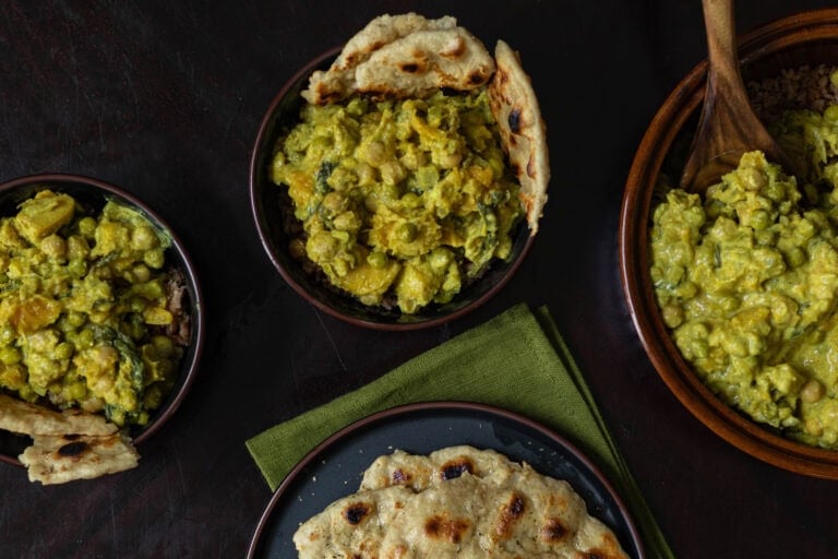 Two bowls of Butternut Squash Chickpea Curry and naan, a serving bowl of curry and a plate of naan.