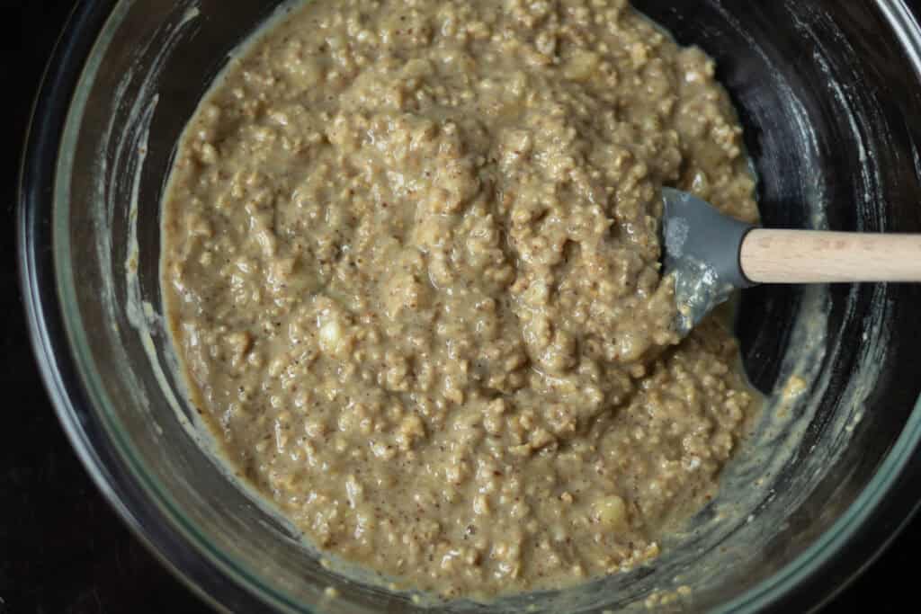 Banana Nut Muffin Batter in a large glass bowl with a gray spatula.