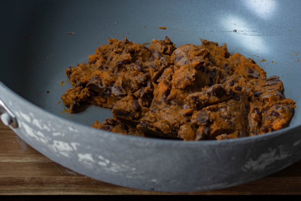 Mashed pumpkin puree and black beans in a metal pan.