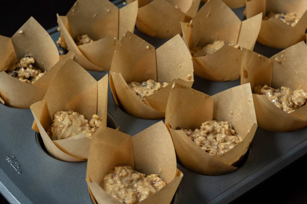 Muffin batter in a lined muffin tin.