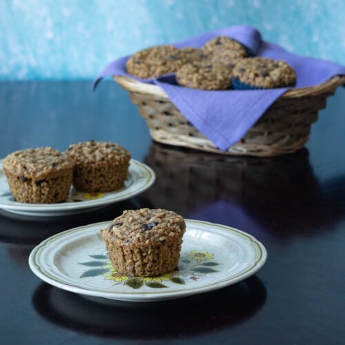 Two plates with peanut butter chocolate chip muffins with a basket of the remaining muffins in the background.