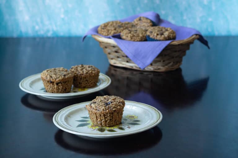 Two plates with peanut butter chocolate chip muffins with a basket of the remaining muffins in the background.
