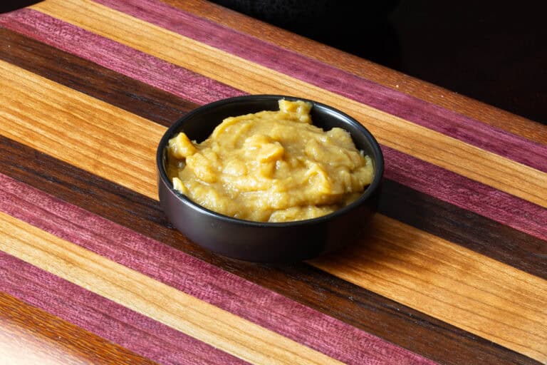 Bowl of homemade garlic sauce sitting on a wooden cutting board.