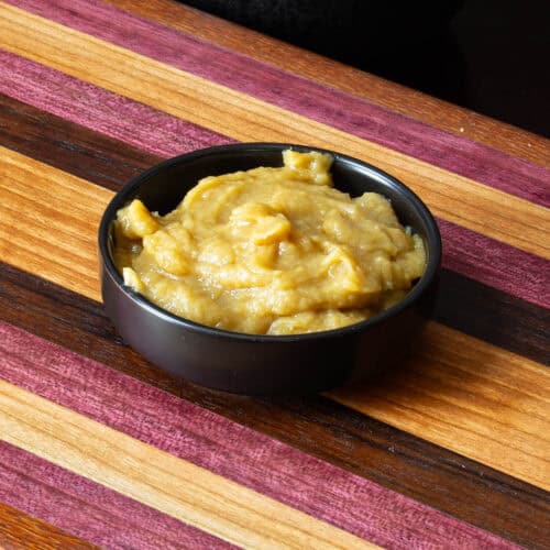 Bowl of homemade garlic sauce sitting on a wooden cutting board.