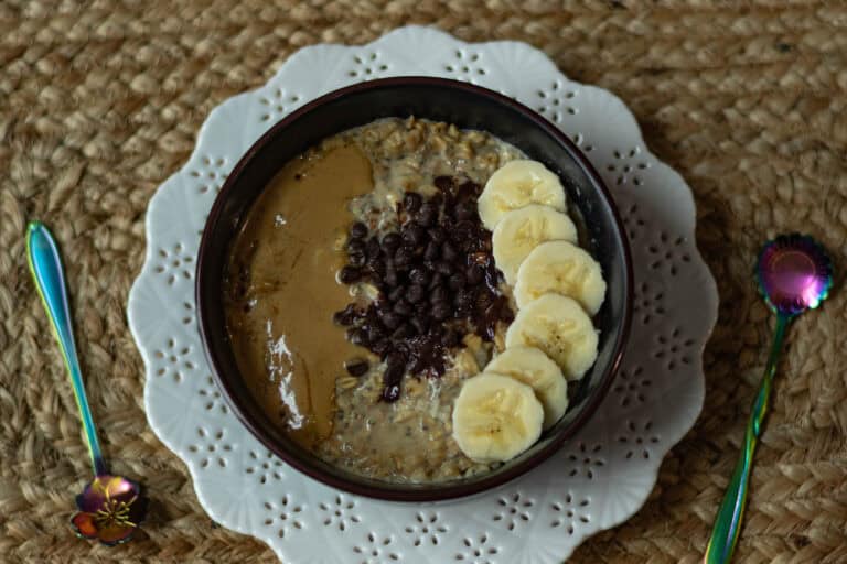 Overnight Oats topped with sliced bananas, melted chocolate chips, and peanut butter.