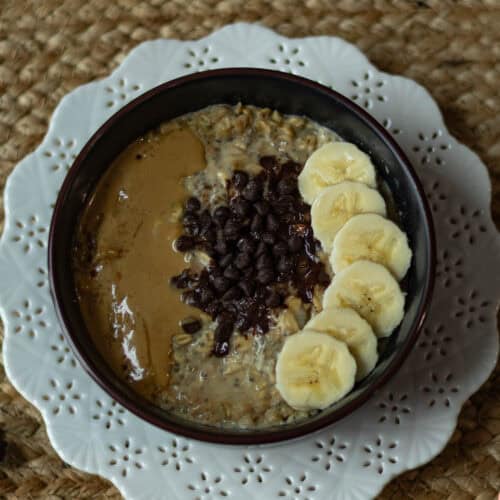 Overnight Oats topped with sliced bananas, melted chocolate chips, and peanut butter.
