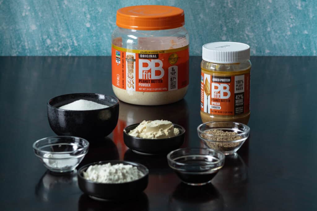 Peanut butter cookie ingredients - flour, protein powder, PB fit powder, PB fit peanut butter spread, ground flax seeds, sugar, baking powder, baking soda and salt.