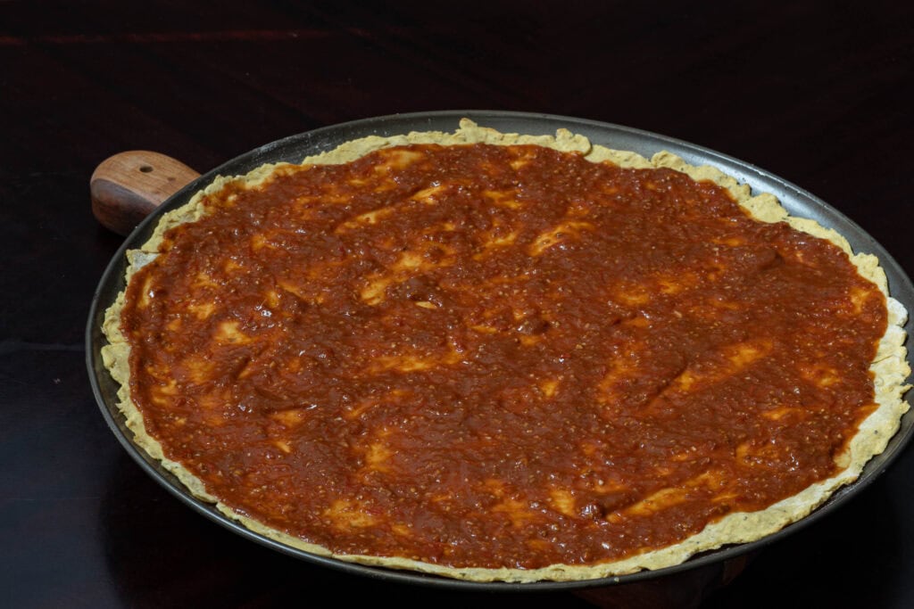 Pre-cooked pizza crust with tomato sauce.