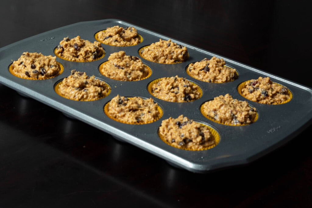 Silver muffin tin with uncooked muffin batter.