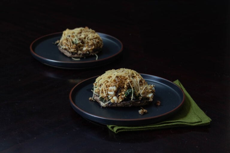 Two plates with stuffed portobello mushrooms.