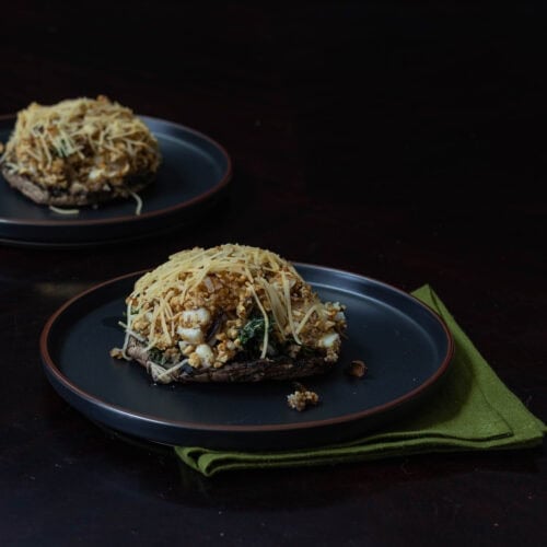 Two plates with stuffed portobello mushrooms.