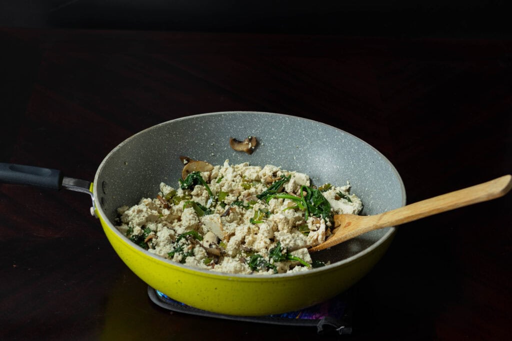 Crumbled tofu with cooked veggies in a large pan.