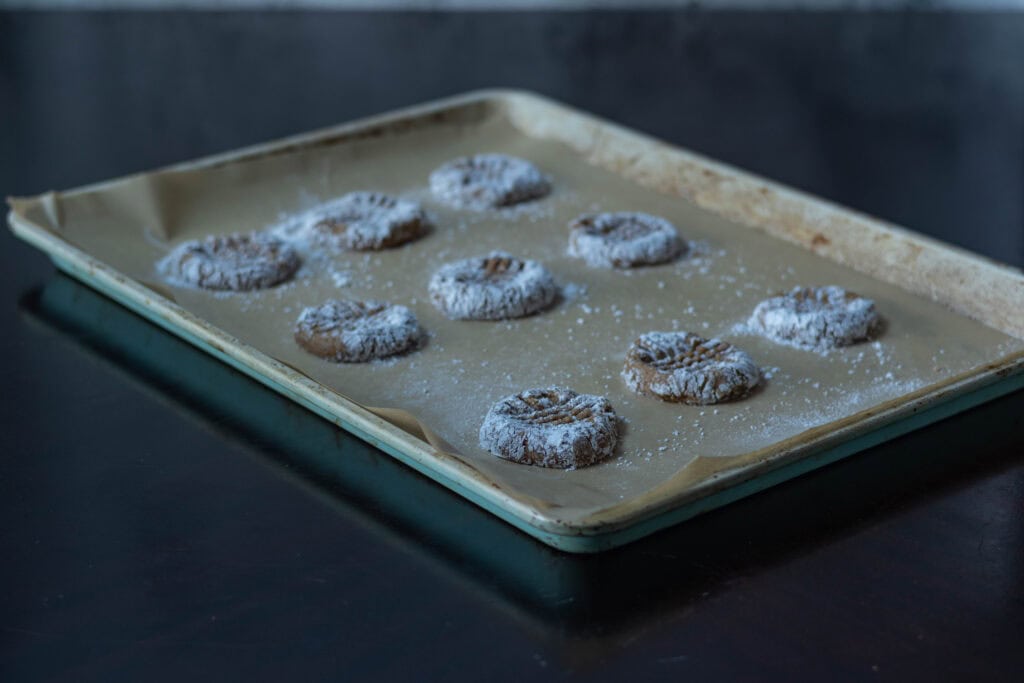 Uncooked almond butter cookie dough sitting on a parchment paper-lined baking sheet.