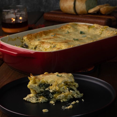 Plate with butternut squash lasagna, large casserole dish with remaining butternut squash lasagna in the background.