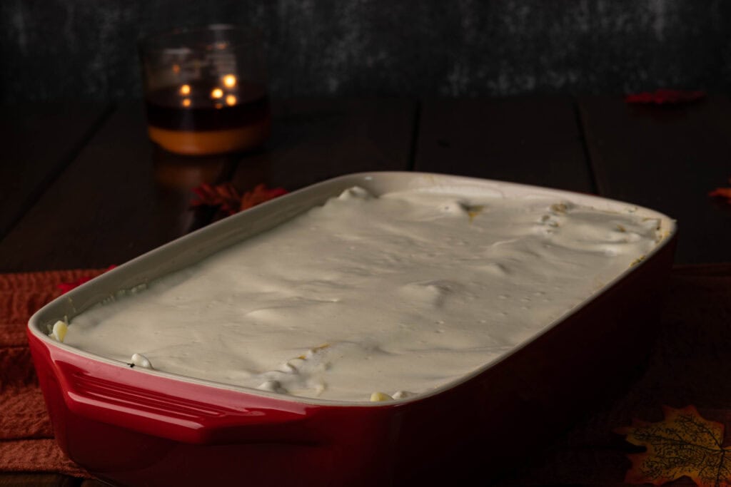 Uncooked butternut squash lasagna in a large casserole dish topped with vegan liquid mozzarella.