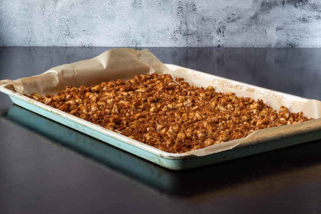 Seasoned and cooked crumbled tofu on a parchment paper-lined baking sheet.
