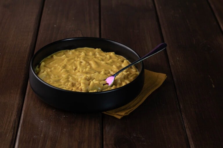 Upgraded vegan mac and cheese in a large black bowl sitting on a wooden table.