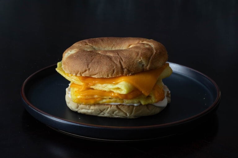 Bagel breakfast sandwich with vegan eggs, mayo and gooey melted cheese slices.