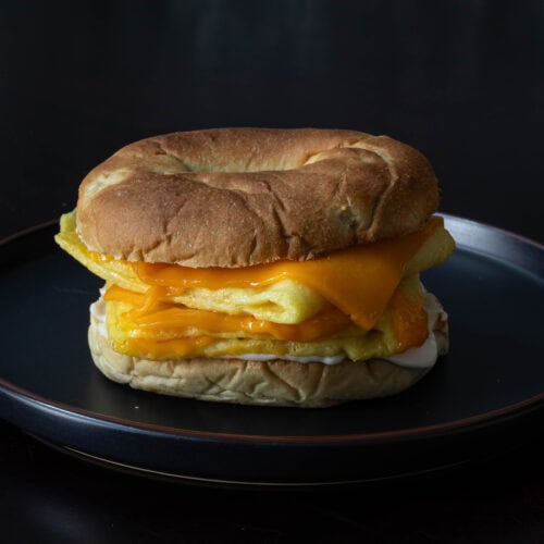 Bagel breakfast sandwich with vegan eggs, mayo and gooey melted cheese slices.