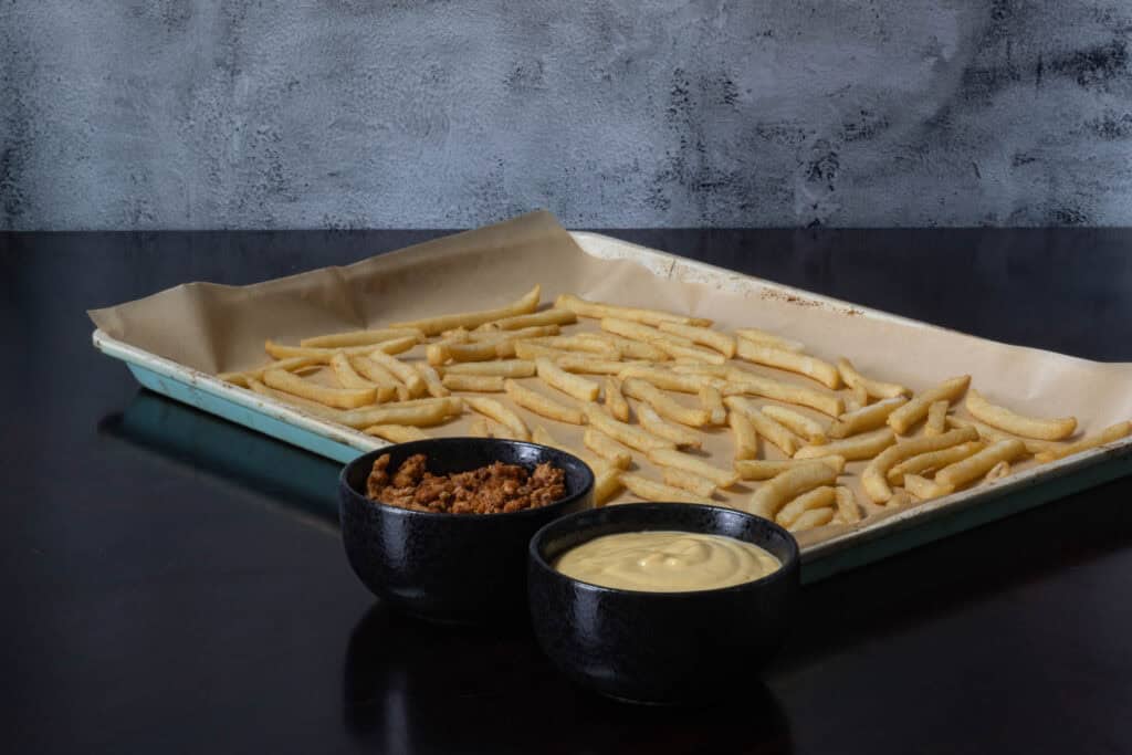 Loaded fries ingredients - french fries, seasoned tofu crumbles and vegan cheese sauce.