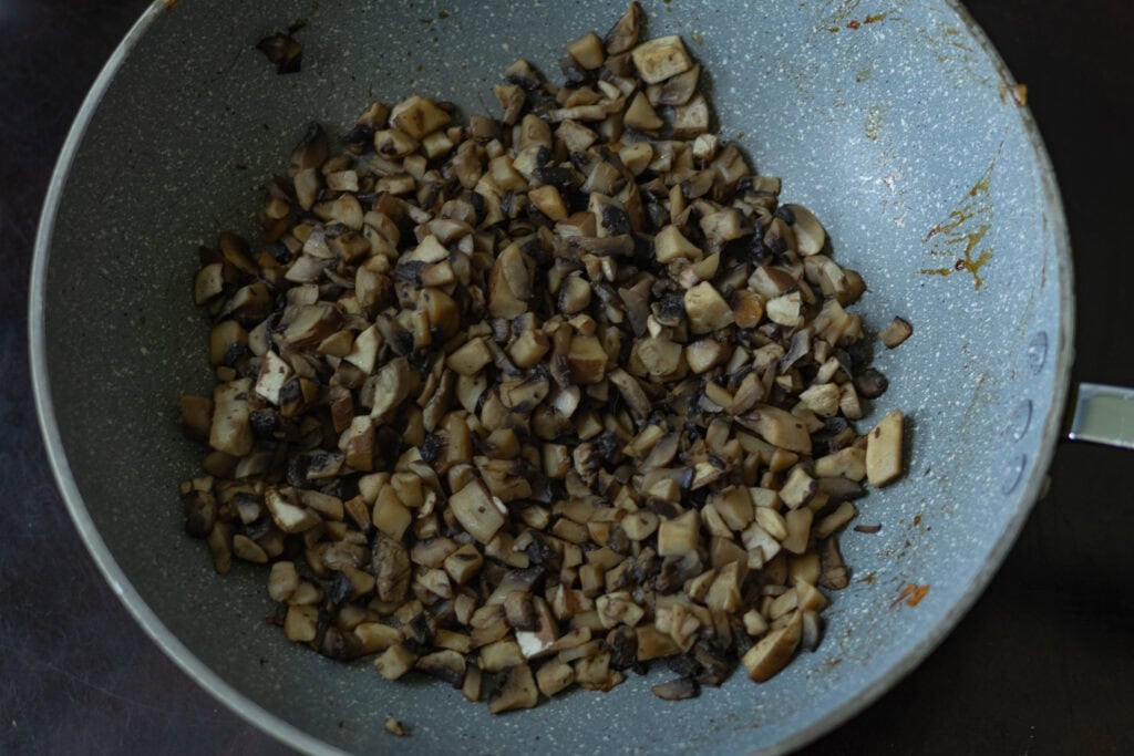 Cooked finely chopped mushrooms in a pan.