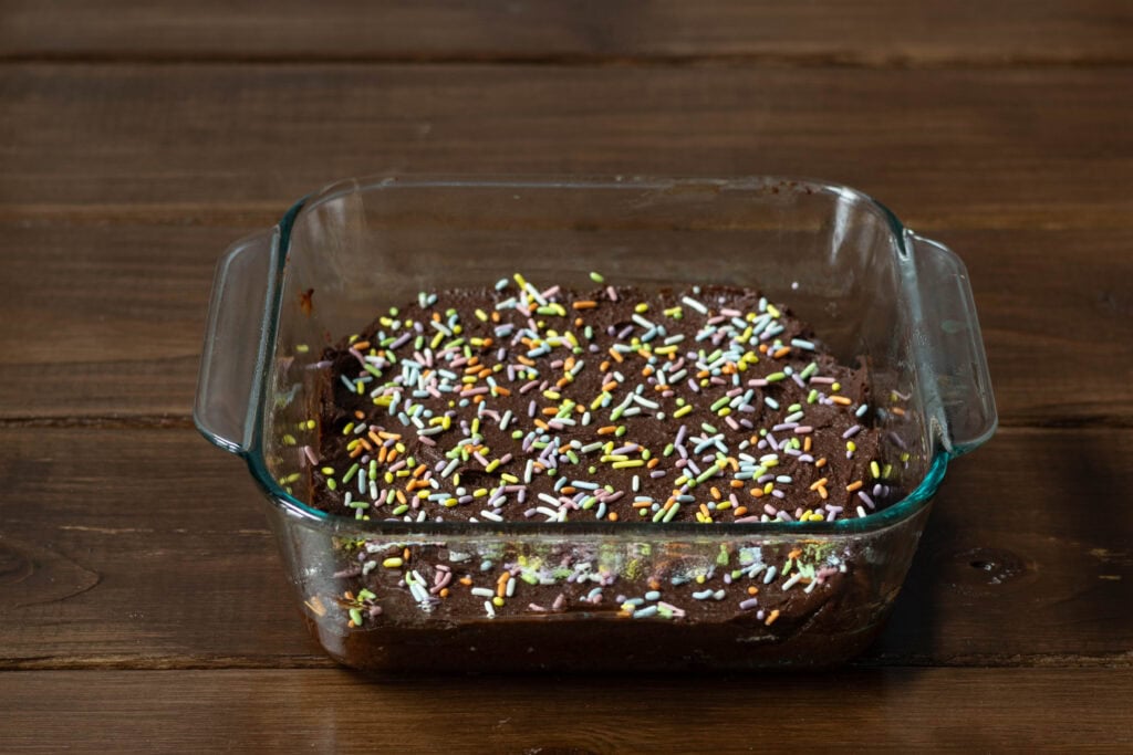 Brownie batter in square glass pan.