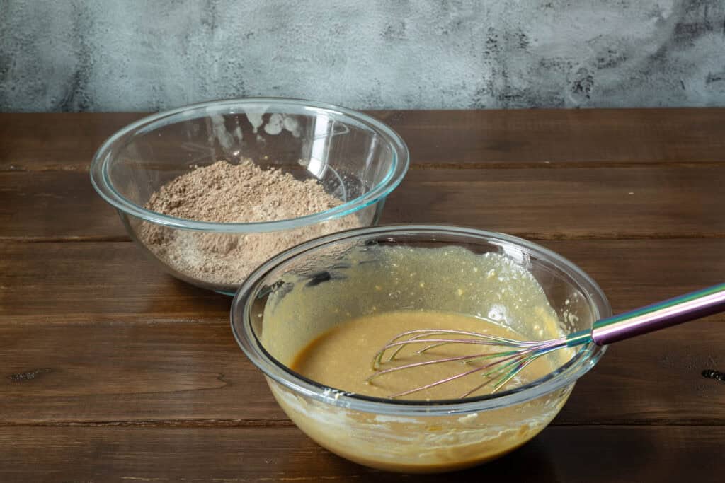 Large bowl of mixed wet ingredients and another bowl of mixed dry ingredients.