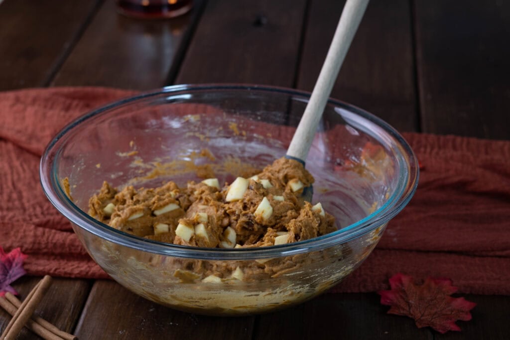 Large glass bowl full of pumpkin apple muffin batter.