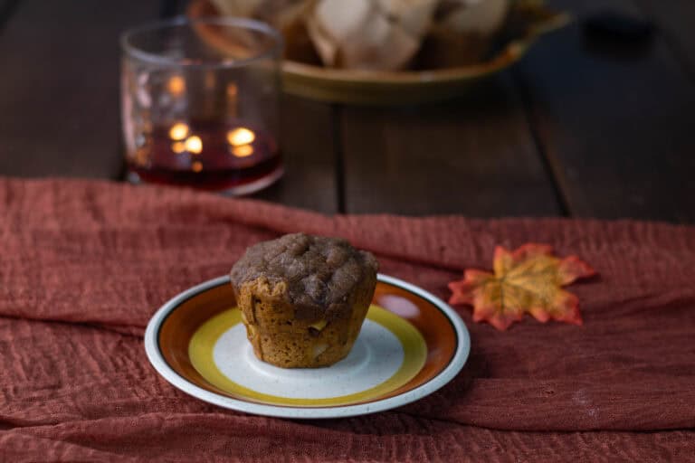 Fluffy apple pumpkin muffin on a plate, fall decorated scene.