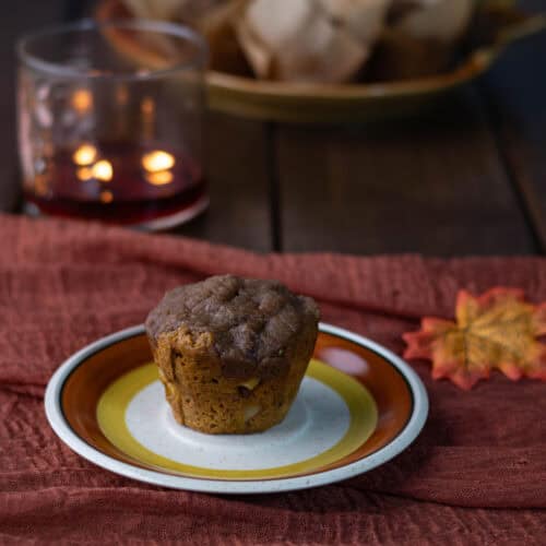 Fluffy apple pumpkin muffin on a plate, fall decorated scene.