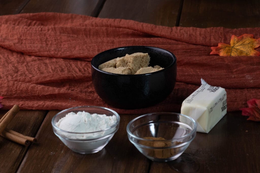 Pumpkin apple muffin topping ingredients sitting on a table - brown sugar, flour, spices, and butter.