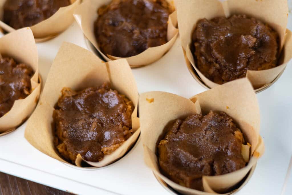 Uncooked apple pumpkin muffins topped with brown sugar crumble.