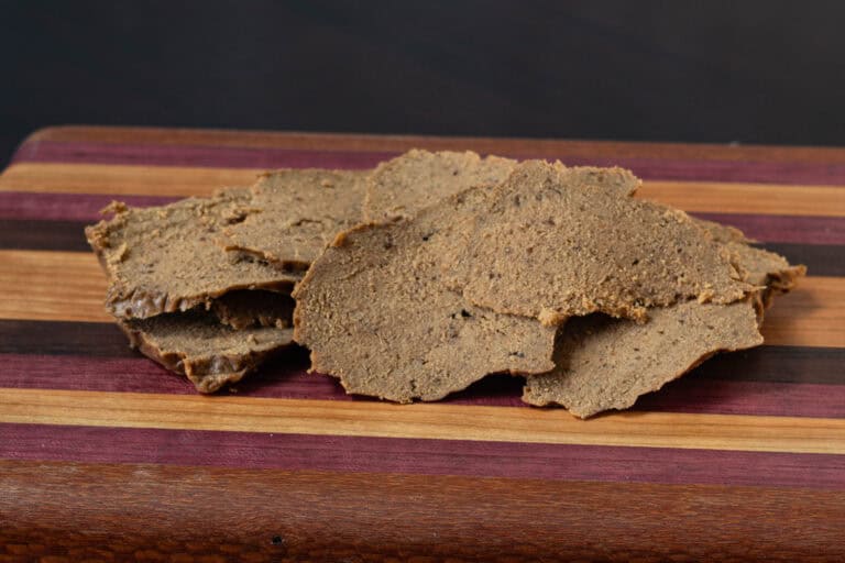 Shaved seitan steak sitting on a wooden cutting board.