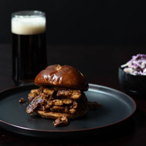 Shredded BBQ Seitan Sandwich on a black plate.