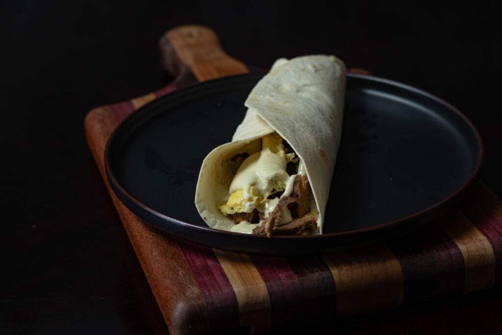 Seitan steak, vegan eggs and vegan queso in a tortilla.