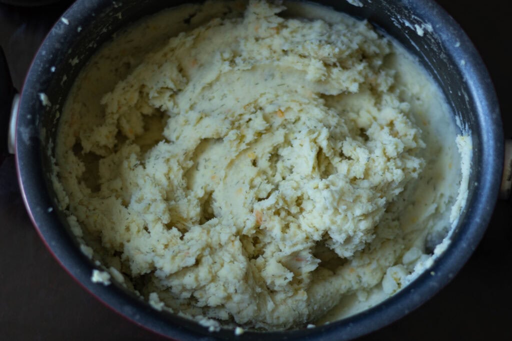 Large pot with mashed potato, sour cream, dill and cheese mixture.