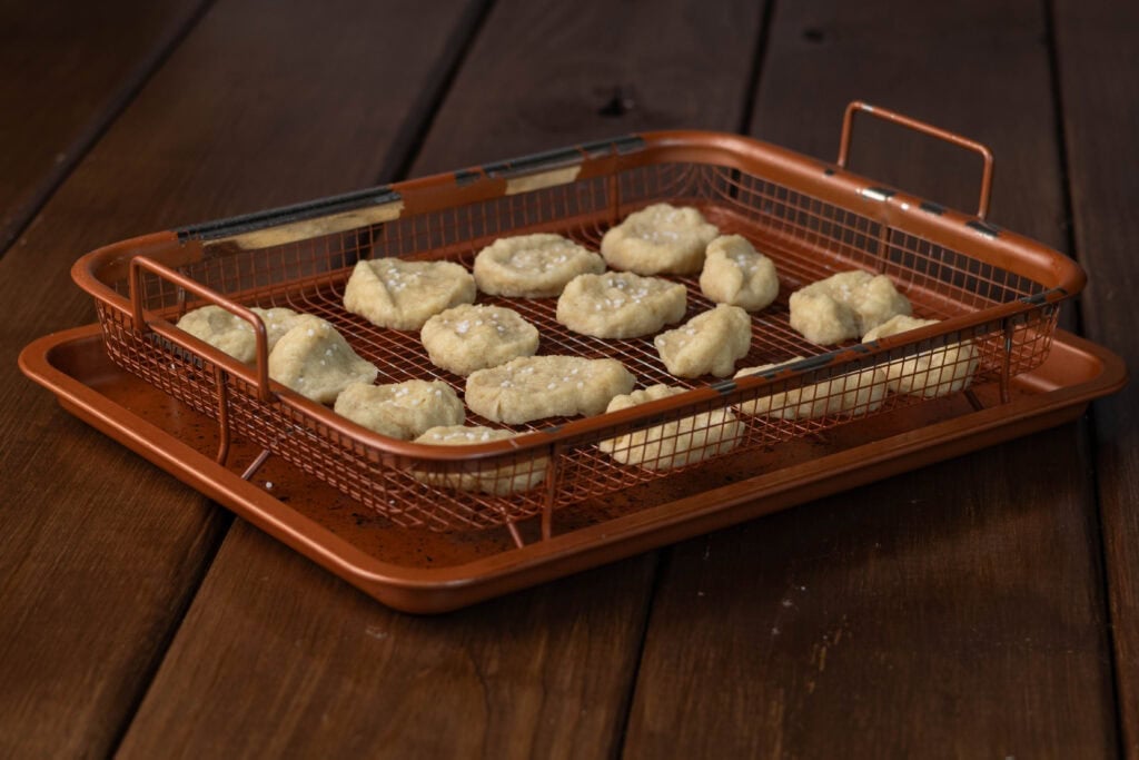 Uncooked pretzel bites on a copper crisping tray.