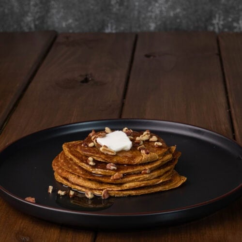 High protein pancakes topped with syrup, chopped pecans and a pad of butter.