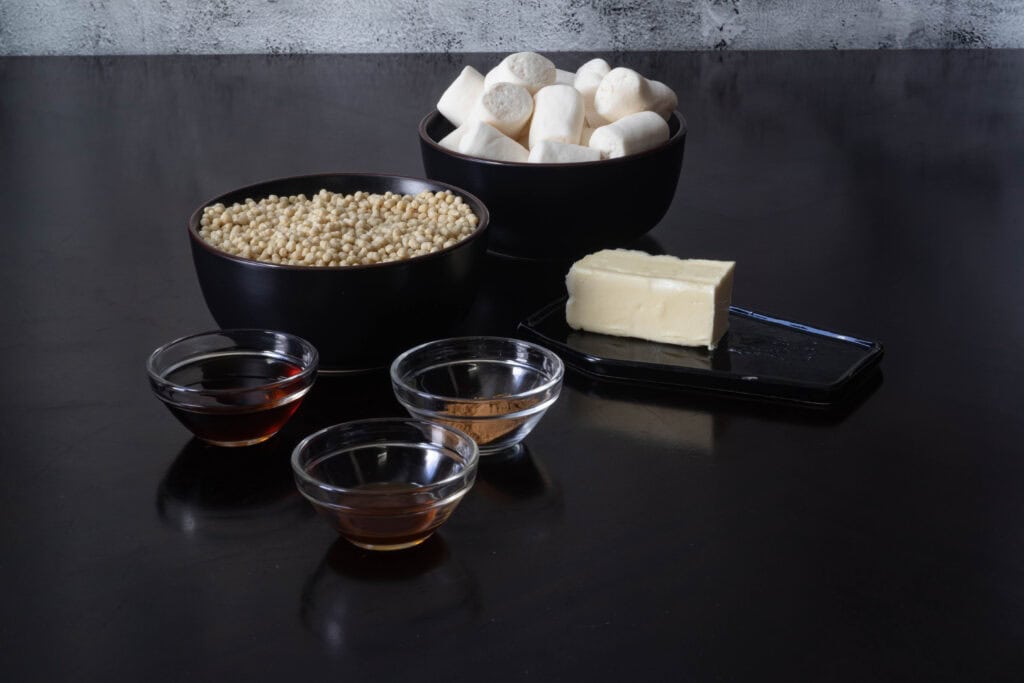 Ingredients sitting on a table - syrup, vanilla extract, spices, butter, edamame puffs and marshmallows.