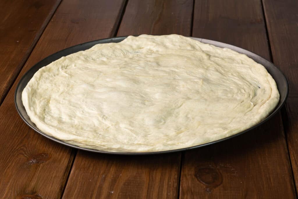 High Protein Pizza Dough spread out on a large pizza pan.