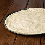 High Protein Pizza Dough spread out on a large pizza pan.