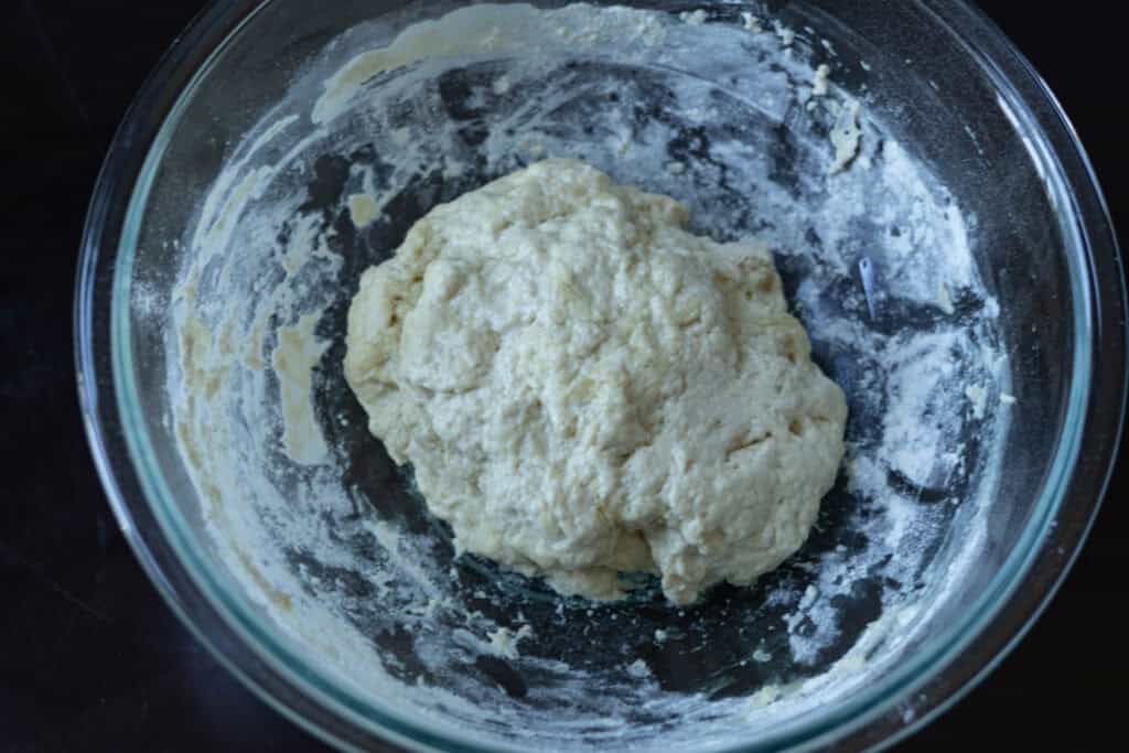 High protein pizza dough in a large glass bowl before proof.
