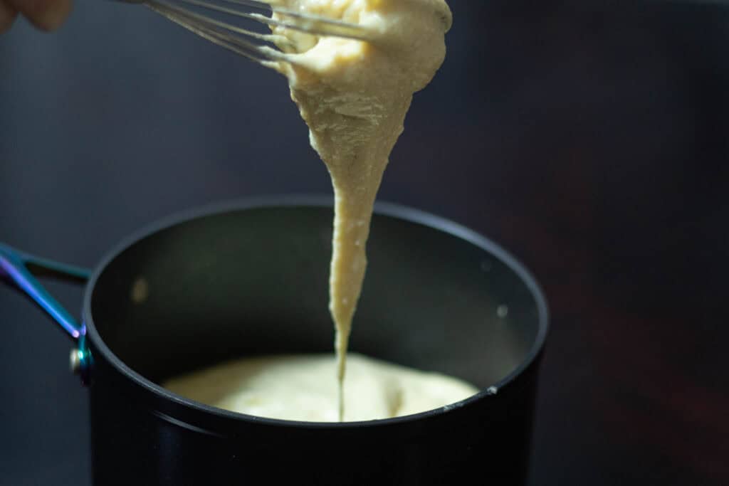 Stretchy soy mozzarella dripping from a whisk.
