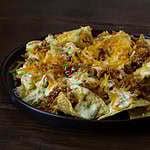 Plate of loaded nachos with shredded BBQ tofu, vegan cheese, and cashew queso.