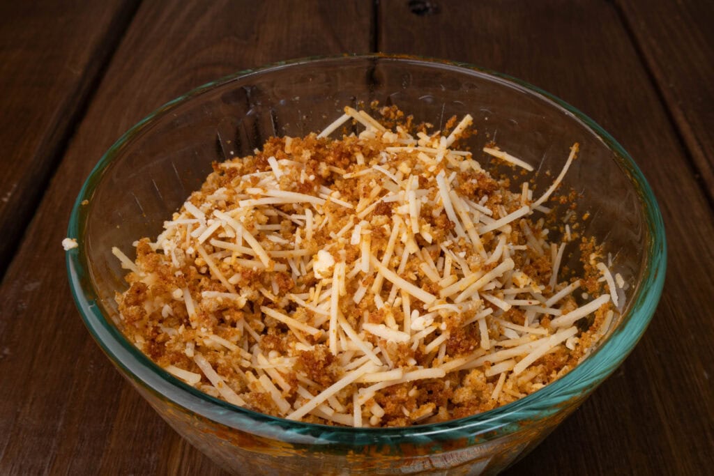 Glass bowl with seasoned breadcrumbs and vegan parmesan.