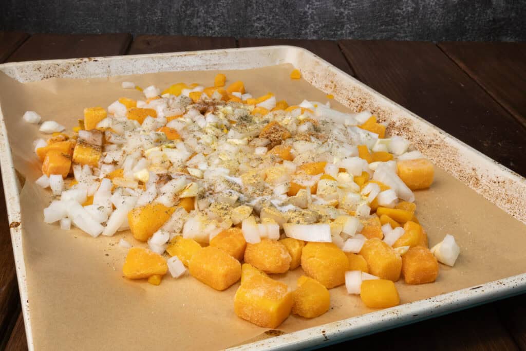 Uncooked veggies on a parchment paper lined baking sheet.