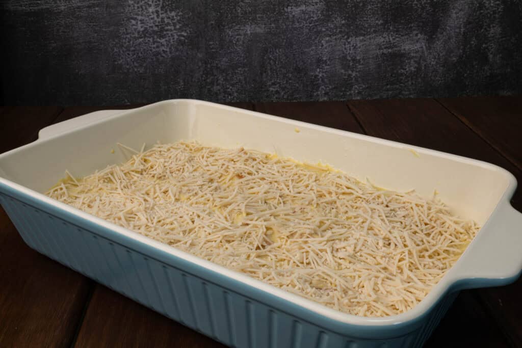 Butternut squash pasta in a casserole dish with vegan parmesan sprinkled on top.