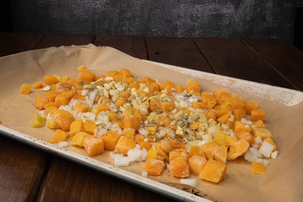 Uncooked veggies on a parchment paper lined baking sheet.