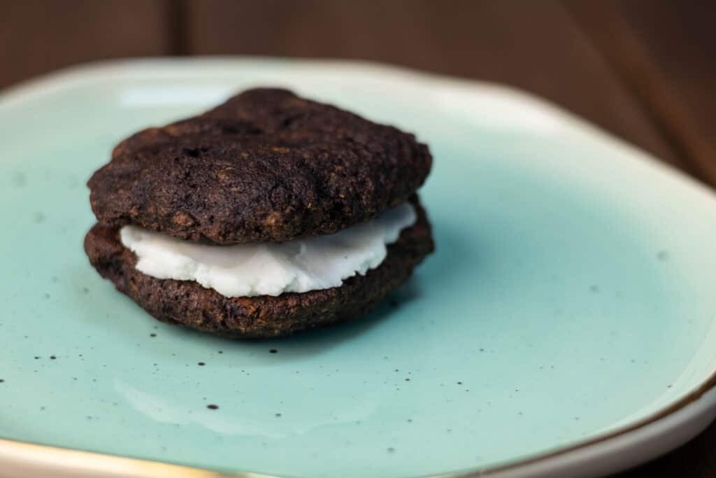 Chocolatey seitan sandwich cookie on a plate.