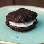 Chocolatey seitan sandwich cookie on a plate.